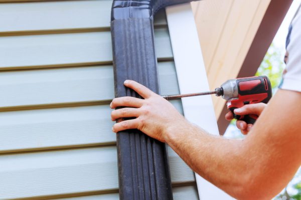 Installation rain gutters on roof with installation of downpipes downspout bends