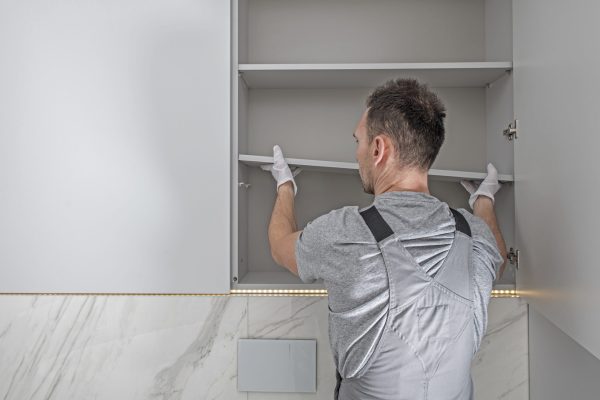 Caucasian Men Installing Modern Bathroom White Cabinets. Working Furniture Specialist.